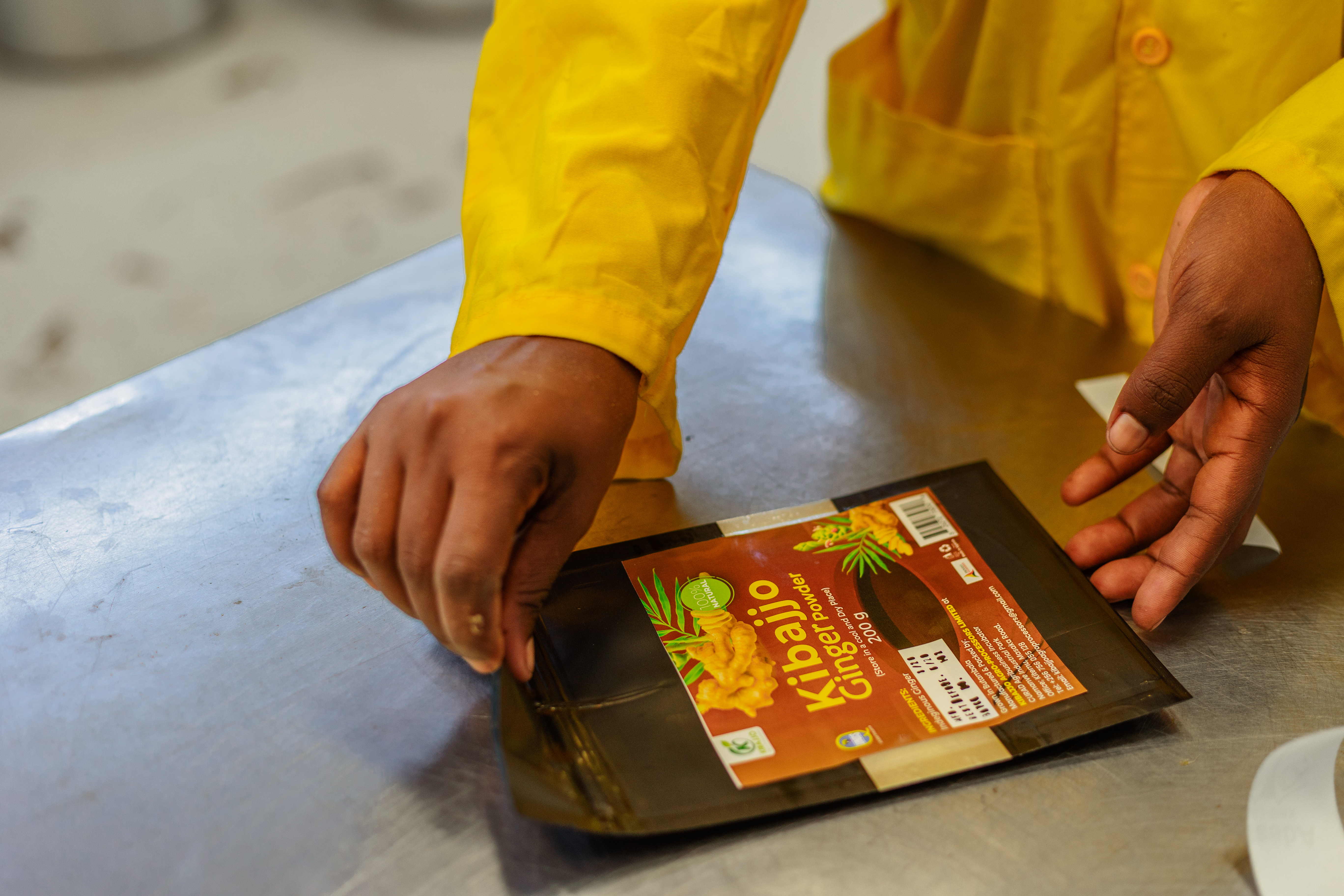 Hands closing a labelled Kibajjo ginger powder pouch